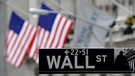 Ein Straßenschild der Wall Street in New York vor US-Flaggen. | Bild: picture alliance / dpa