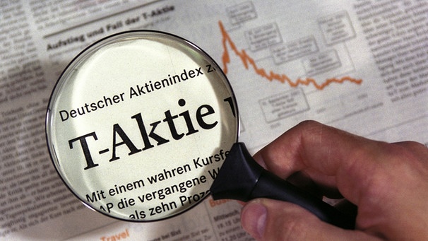 Durch eine Lupe, die über einen Zeitungsartikel gehalten wird, erscheint der Text "Deutscher Aktienindex T-Aktie" | Bild: dpa/picture-alliance/Ulrich Baumgarten
