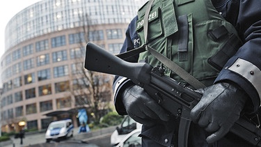 Mit einer Maschinenpistole in der Hand steht ein Polizeibeamter am 17.11.2010 vor dem Bundesinnenministerium in Berlin | Bild: picture-alliance/dpa