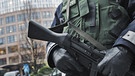 Mit einer Maschinenpistole in der Hand steht ein Polizeibeamter am 17.11.2010 vor dem Bundesinnenministerium in Berlin | Bild: picture-alliance/dpa