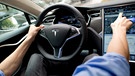 Ein Mann sitzt am 17.08.2015 in München (Bayern) in einem Tesla Model S auf dem Fahrersitz vor einem Showroom des Autoherstellers. | Bild: picture-alliance/dpa