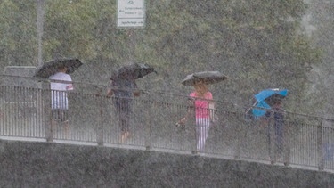 Passanten laufen durch den Regen  | Bild: picture-alliance/dpa/Armin Weigel