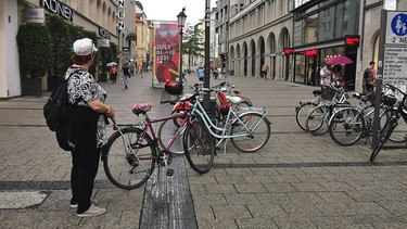 Über einem Blindenleitstreifen stehen Fahrräder und dahinter ein fünf Meter hohes Filmplakat. | Bild: BR / Sandra Demmelhuber