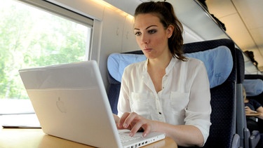 Frau sitzt im Zug und arbeitet am Laptop | Bild: picture-alliance/dpa