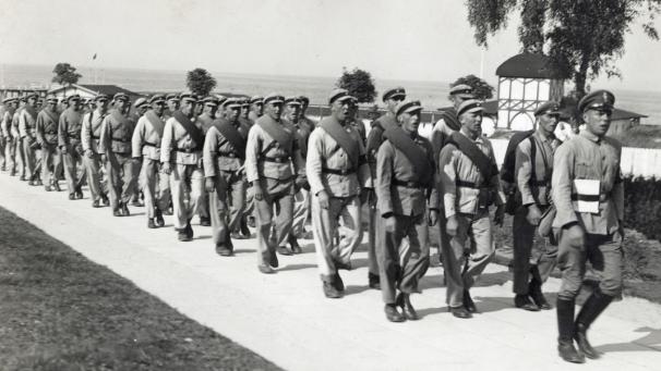 Männer in Uniformen des Freiwilligen Arbeitsdienstes (FAD) Griebenow marschieren im September 1933 mit einem Marschlied über die Strandpromenade des Ostseebades Göhren auf der Insel Rügen. | Bild: picture-alliance/dpa