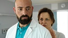 Dr. Hoffmann (Anton Noori, links) im Krankenzimmer mit Caroline (Martina Gedeck) nach ihrer Tablettenvergiftung.
| Bild: BR/Lotus-Film/ORF/Petro Domenigg