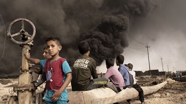 Qayyara, Irak: Im Oktober 2016 wurden in Qayyara Kinder gesehen, die von den Kämpfern des IS bei brennenden Rohölfeldern hinterlassen wurden, als sie sich zurückzogen. Was ist zu tun, um die Hunderttausenden von Kindern zu retten, die drei Jahre lang unter dem IS aufgewachsen sind? Wie können wir verhindern, dass diese Kinder der Nährboden für den Terrorismus von morgen sind? | Bild: BR/CALA Filmproduktion/Alessio Romenzi