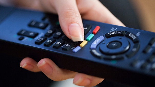 Frau drückt den Knopf auf einer Fernseh-Fernbedienung | Bild: picture-alliance/dpa