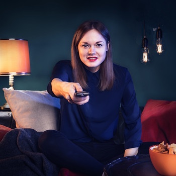Szene mit Host Vanessa Schneider in einem Wohnzimmer mit Fernbedienung in der Hand | Bild: BR