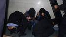 Gefangene mit Kapuzen werden von Uniformierten kontrolliert. | Bild: xinjiangpolicefiles 