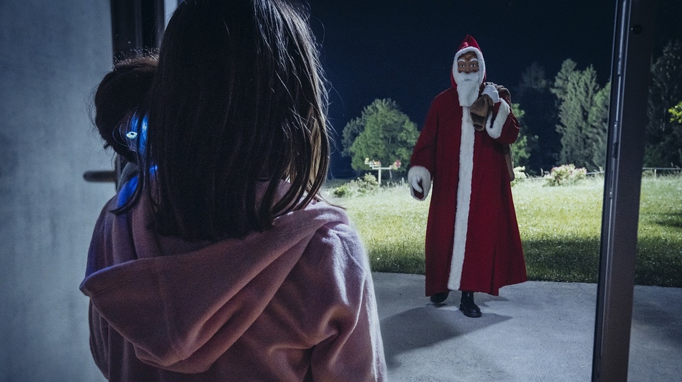 Von links: Ihre sprechende Puppe führt Gretchen Grein (Lilly Walleshauser) in der Nacht ins Wohnzimmer, wo sie den Weihnachtsmann erwartet. | Bild: BR/Tellux-Film GmbH/Hendrik Heiden