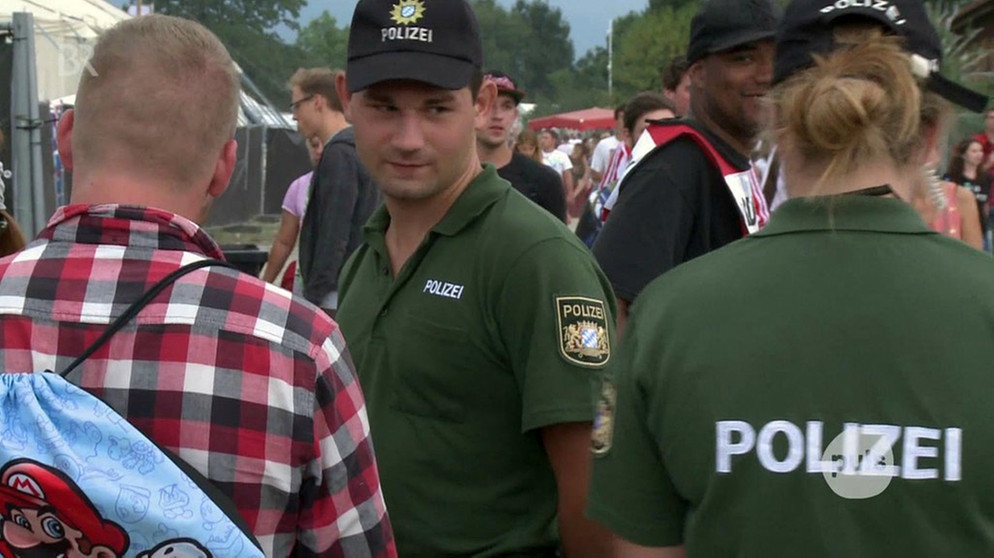 Zwei Polizisten kontrollieren Festival-Besucher beim Chiemsee Reggae Summer | Bild: BR