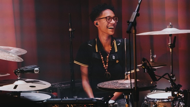 Die Drummerin Philo Tsoungui sitzt lachend hinter ihrem Schlagzeug. | Bild: Mangler