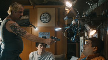 Der Rinselner Drogendealer (Bjarne Mädel) bedroht Lenny und Moritz mit einer Waffe im Kinderzimmer in einer Szene aus der deutschen Netflix-Serie "How To Sell Drugs Online (Fast)" | Bild: Netflix/Bernd Spauke