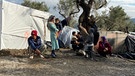 Bewohner des Flüchtlingslagers Moria auf der griechischen Insel Lesbos stehen und knien vor einem Zelt, im Hintergrund stehen Olivenbäume  | Bild: privat