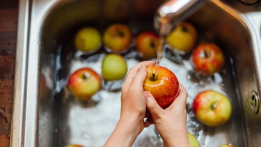 Frau wäscht Äpfel in Spühle | Bild: mauritius-images