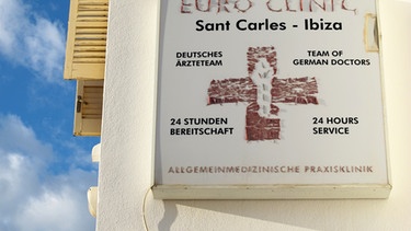 Ein verwittertes Schild weist in deutsch und englisch auf eine deutsche Praxis mit einem deutschen Ärzteteam und einer 24-Stunden-Bereitschaft in Spanien auf Ibiza hin. | Bild: picture alliance / ZB | Jens Kalaene