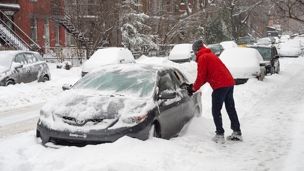 Zwei Menschen befreien ein Auto von sehr viel Schnee | Bild: picture-alliance/dpa