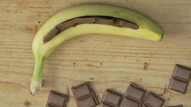Die mit Schokoladenstückchen gefüllte Banane liegt auf einem Tisch.  | Bild: BR