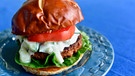 Auf einem blauen Teller ist ein Burger mit fleischlosem Patty von Beyond Meat zu sehen. | Bild: mauritius-images