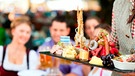 In einem bayerischen Biergarten wird ein üppiges Brotzeitbrett mit Wurst und Käse serviert | Bild: mauritius-images