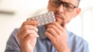 Mann überprüft das Haltbarkeitsdatum auf einem Tablettenblister | Bild: mauritius images