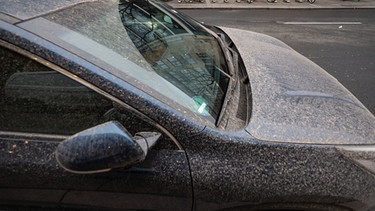 Ein Auto ist in der Innenstadt von rötlichem Staub bedeckt. | Bild: dpa-Bildfunk/Marijan Murat