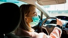 Eine Frau fährt Auto und trägt dabei eine Maske | Bild: mauritius-images