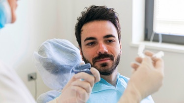 Zahnärztin zeigt ihrem Patienten eine Aufbissschiene | Bild: mauritius-images