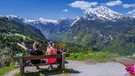 Pärchen sitzt auf einer Bank in den bayerischen Bergen | Bild: mauritius-images