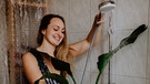 Eine Frau gießt ihre Pflanze und trägt dabei ein Ballkleid | Bild: Picaro Photography