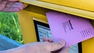 Eine Hand wirft Briefwahlunterlagen in einen Briefkasten | Bild: dpa/picture alliance, Stephan Goerlich