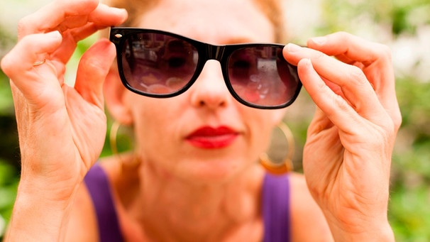 Frau hält Sonnenbrille vor das Gesicht | Bild: mauritius images