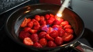 Erdbeeren in einer Pfanne, die flambiert werden | Bild: mauritius images / Katharina Hild