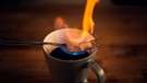 Auf einer Tasse liegen brennende Zuckerwürfel  | Bild: BR