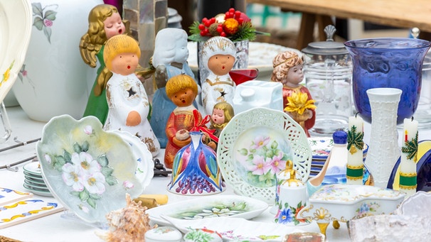 Mehrere Keramikfiguren und Geschirr stehen auf einem Tisch bei einem Flohmarkt | Bild: mauritius images