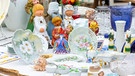 Mehrere Keramikfiguren und Geschirr stehen auf einem Tisch bei einem Flohmarkt | Bild: mauritius images