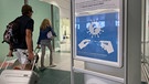 Reisende am Münchner Flughafen gehen an einem Corona-Test-Schild vorbei | Bild: dpa/picture alliance