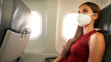 Flugpassagierin trägt eine Maske | Bild: mauritius images