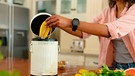 Frau wirft Bananenschale in einen Eimer | Bild: maurtitius images