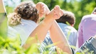 Menschen liegen im Gras und strecken ihre Füße in die Luft | Bild: colourbox.com