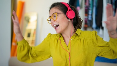 Eine Frau hört Musik mit Kopfhörern | Bild: mauritius-images