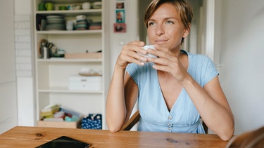Frau genießt eine Tasse Kaffee in ihrer Küche | Bild: mauritius images / Westend61 / Kniel Synnatzschke