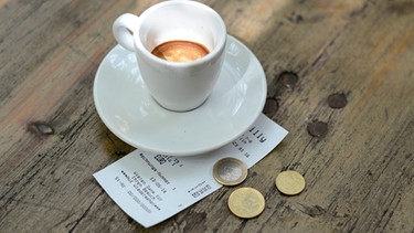 Kassenbon liegt neben einer Tasse mit Espresso. | Bild: mauritius images