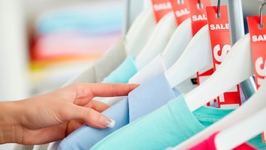 Reduzierte T-Shirts hänen auf Kleiderbügeln in einem Geschäft | Bild: mauritius images