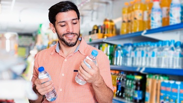 Mann kauft im Supermarkt Wasser ein | Bild: mauritius-images