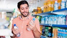 Mann kauft im Supermarkt Wasser ein | Bild: mauritius-images