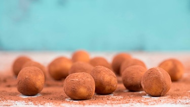 Marzipankartoffeln liegen auf einem Brett mit Kakaopulver. | Bild: mauritius images