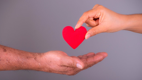 Eine Hand legt ein symbolisches Herz in eine andere Hand. | Bild: mauritius-images