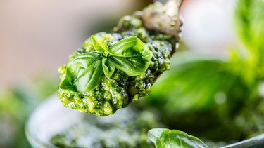 Löffel mit Pesto vor einem Glas | Bild: mauritius images / foodcollection / Gregory Clark
